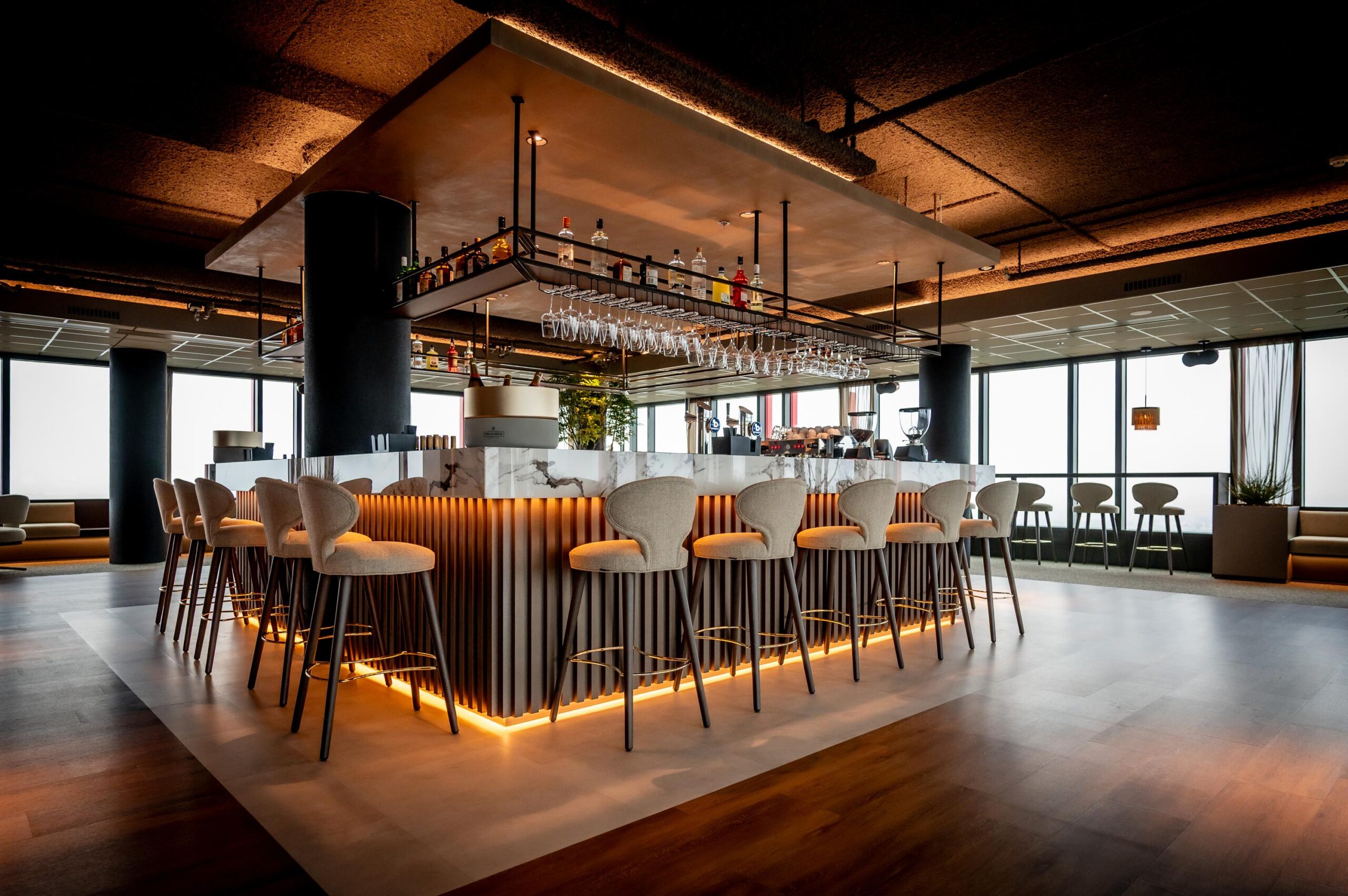 Stijlvol verlichte marmeren bar met moderne barkrukken in een luxe lounge aan de P.J. Oudweg.